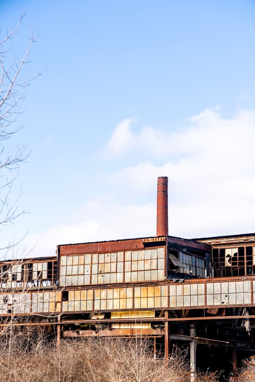 A decaying industrial structure with rusted metal elements under a blue sky.